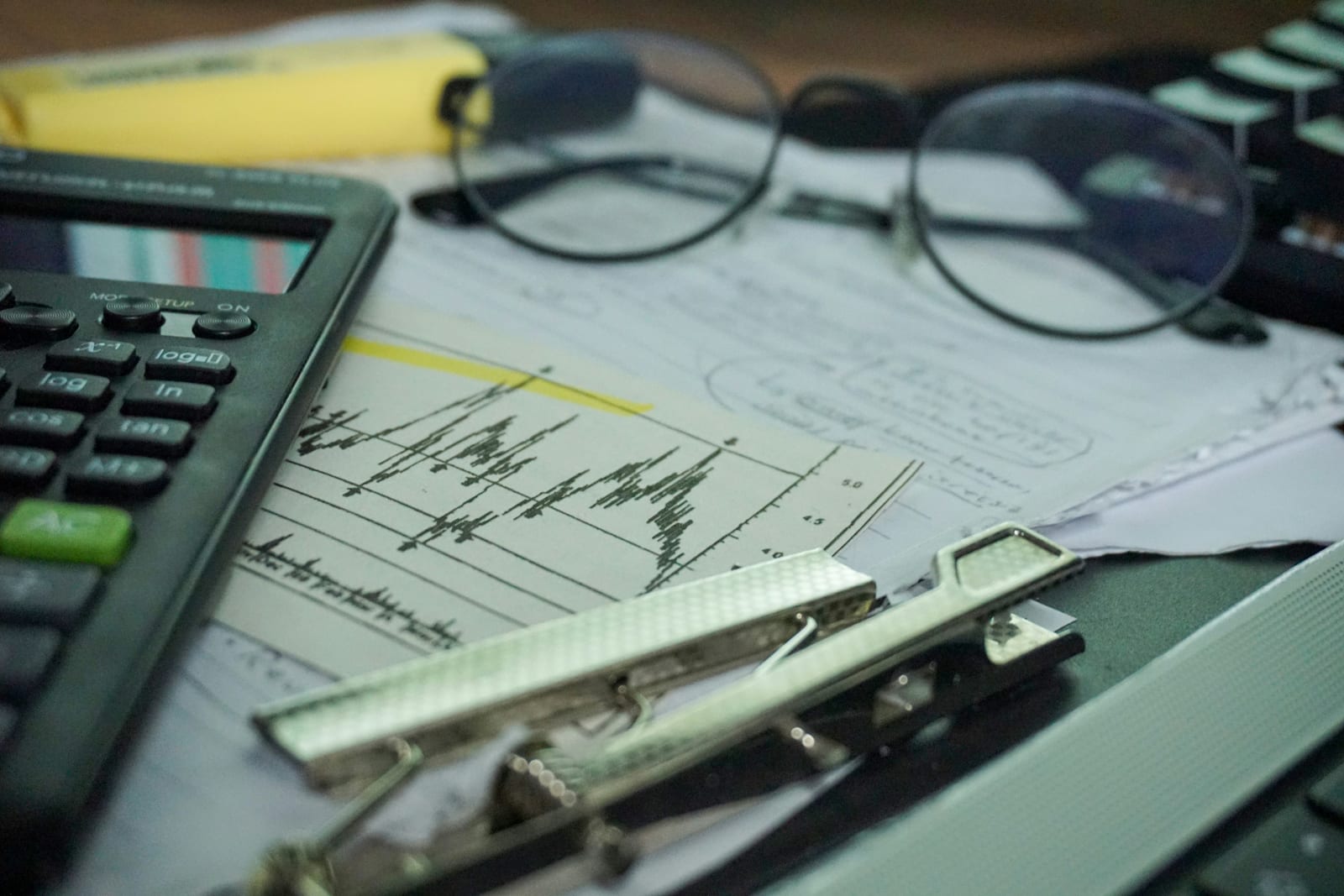 Business owner reviewing performance reports and charts at a desk with a laptop and calculator